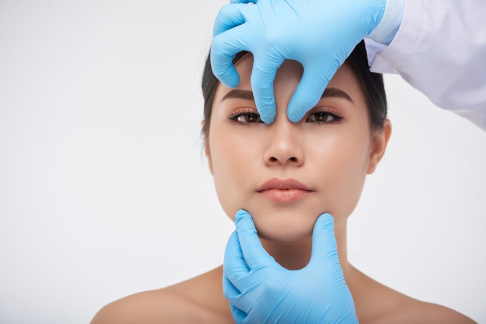 Surgeon checking fthe acial structure of a patient before rhinoplasty for thick skin